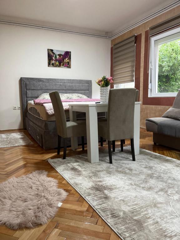 a dining room with a table and chairs and a bed at ALOHA apartment in Novi Pazar