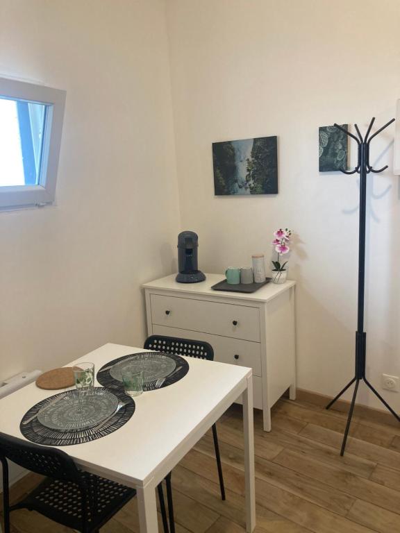 a dining room with a white table and a dresser at Le mini cosy in Gaillon