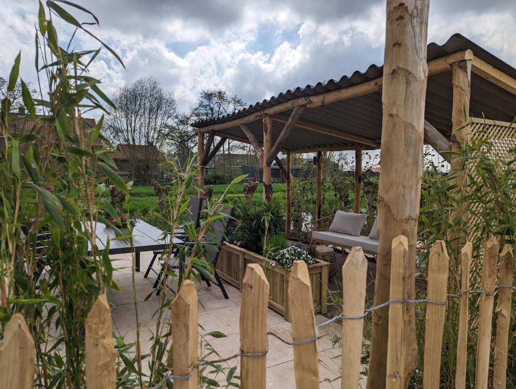 a wooden fence with a wooden pavilion in a garden at Huisje Hartenlust in Bodegraven