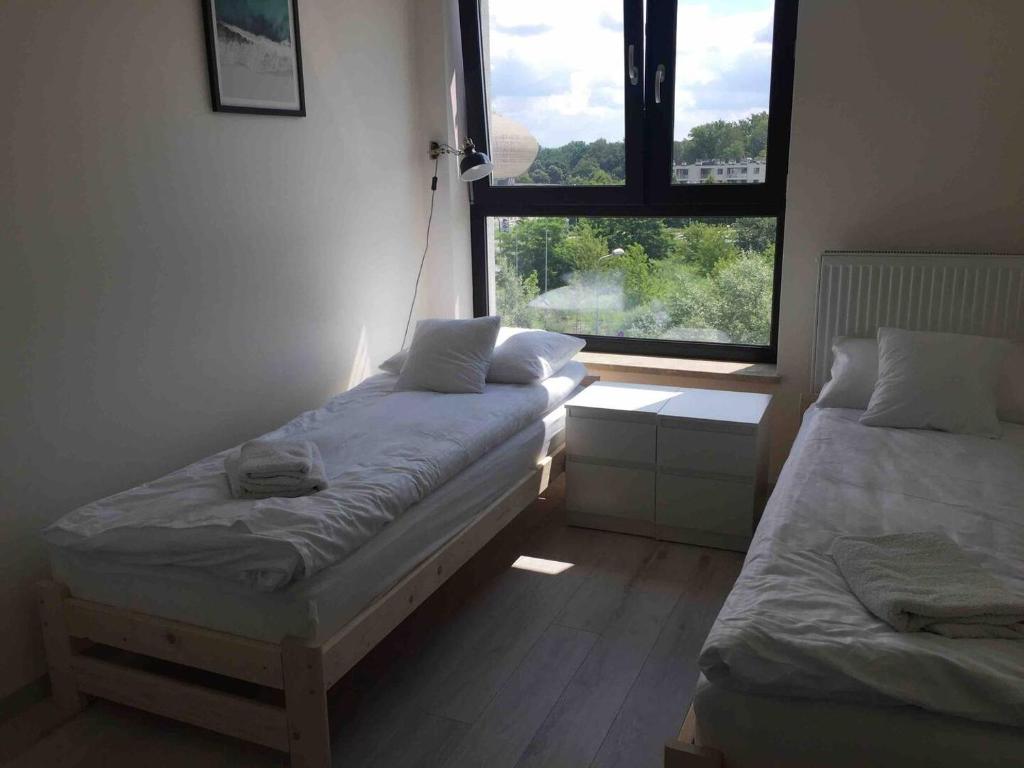 two beds in a room with a window at Apartament Kraków Arena in Krakow