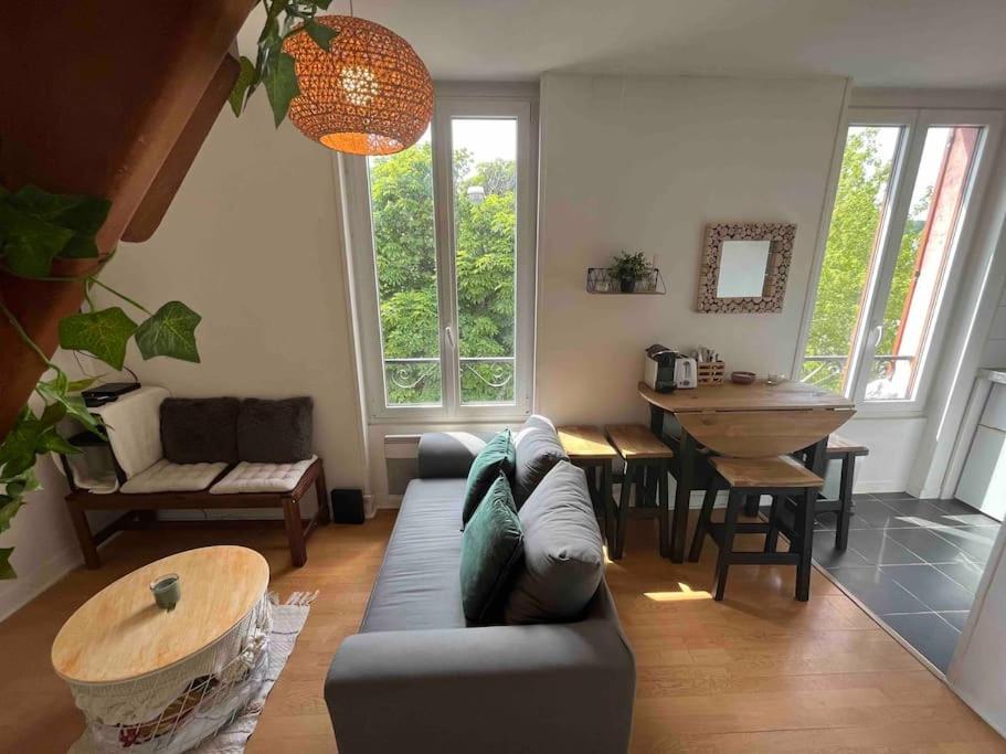 a living room with a couch and a table at Havre de tranquillité entre Paris et Versailles in Chaville