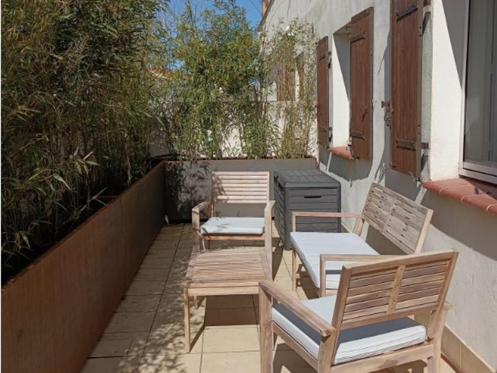 una fila de sillas de madera sentadas en un balcón en Appartement Saintes-Maries-de-la-Mer, 3 pièces, 4 personnes - FR-1-475-110, en Saintes-Maries-de-la-Mer