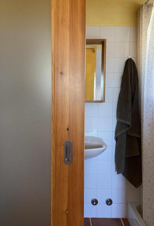a bathroom with a sink and a wooden door at Casa Presente Guesthouse in Carrapateira