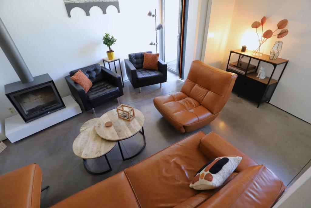 sala de estar con muebles de cuero y chimenea en Aux Berges du Bocq, en Yvoir