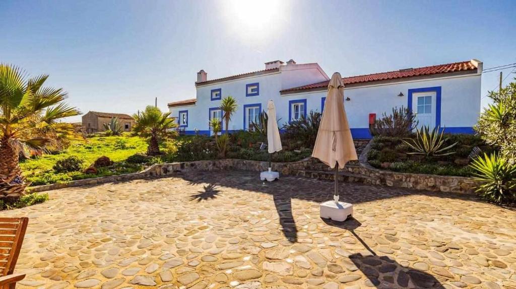 une terrasse avec un parasol et une maison dans l'établissement Casa Presente Guesthouse, à Carrapateira