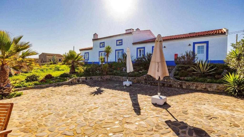 a patio with an umbrella and a house at Casa Presente Guesthouse in Carrapateira