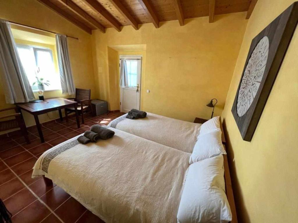 a bedroom with two beds and a table and a piano at Casa Presente Guesthouse in Carrapateira