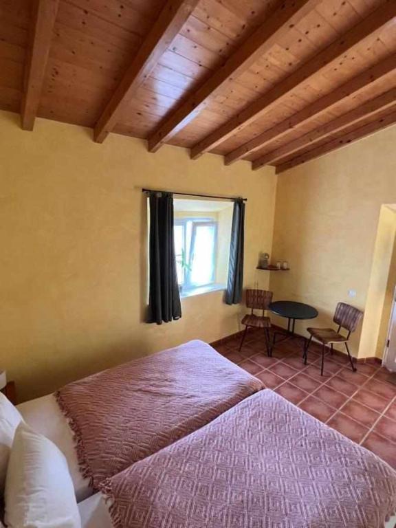 a bedroom with a large bed and a table at Casa Presente Guesthouse in Carrapateira