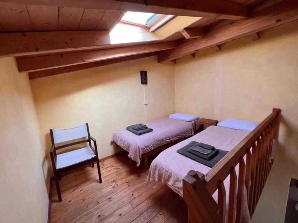 a attic room with two beds and a chair at Casa Presente Guesthouse in Carrapateira