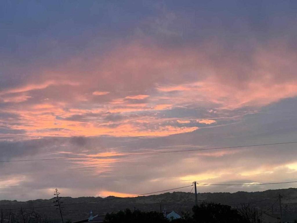 a cloudy sky at sunset with mountains in the background at Casa Presente Guesthouse in Carrapateira