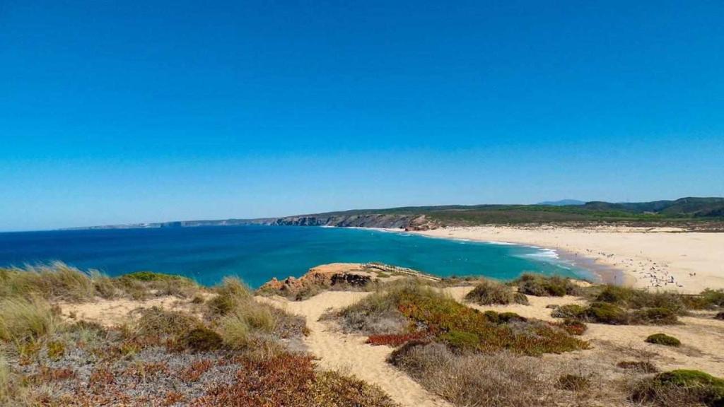 a view of a beach with blue water at Casa Presente Guesthouse in Carrapateira
