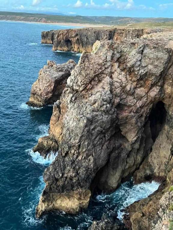 a rocky cliff in the ocean with the water at Casa Presente Guesthouse in Carrapateira