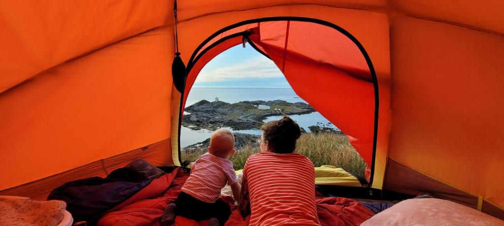 una madre y un bebé mirando fuera de una tienda en Haramsøy One Night Glamping- Island Life North- overnight stay in a tent set up in nature- Perfect to get to know Norwegian Friluftsliv- Enjoy a little glamorous adventure, en Haram