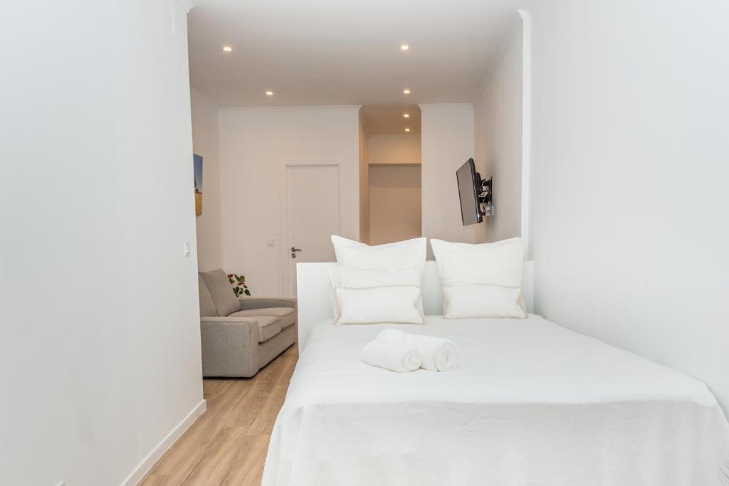 um quarto branco com uma grande cama branca com almofadas brancas em Arrabida House em Setúbal