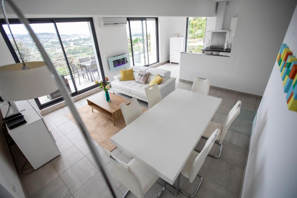 un salon avec une table et des chaises blanches dans l'établissement Villa Malibu by Connexion, à Mandelieu-la-Napoule