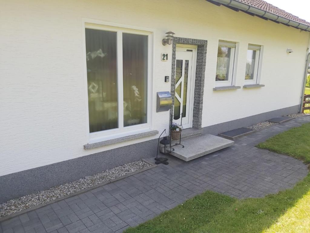 una puerta a una casa con un gato sentado en un porche en Hubis Ferienwohnung, en Olpe