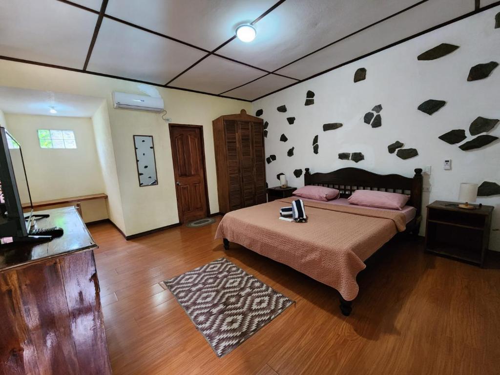 パングラオにあるティップトップ ホテル レスト アンド デリショップのウッドフロアのベッドルーム1室(ベッド1台、テレビ付)