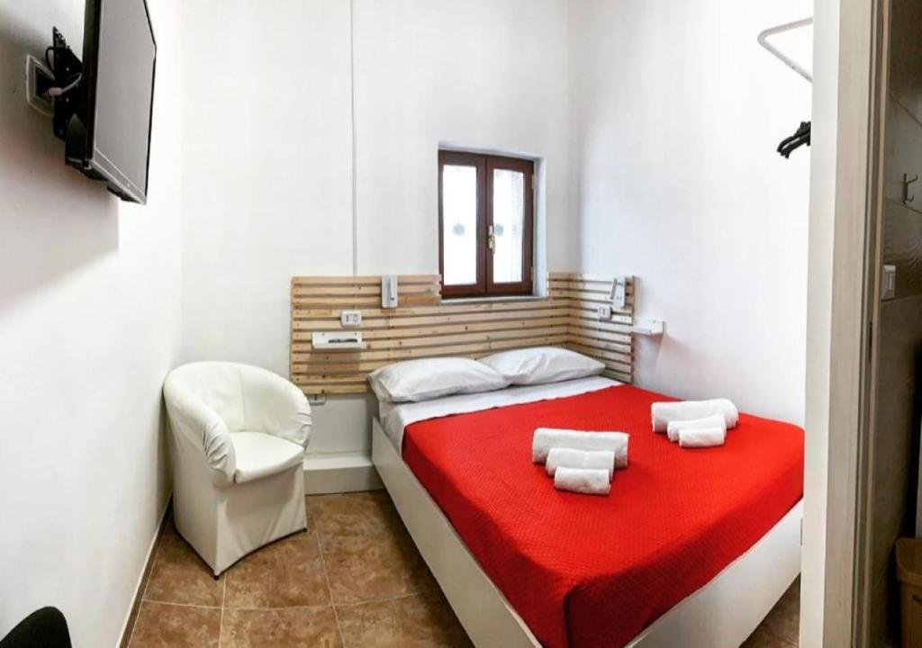 ein Schlafzimmer mit einem Bett mit einer roten Decke und einem Stuhl in der Unterkunft MIRIS home fast and comfortable with self check in 8 minutes walk near Naples airport in Neapel