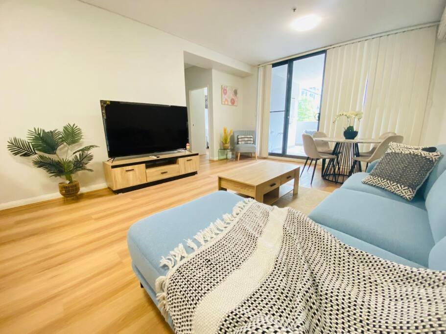 a living room with a blue couch and a flat screen tv at Parramatta Adorable 3Br Apt ParkingBusShopping in Sydney