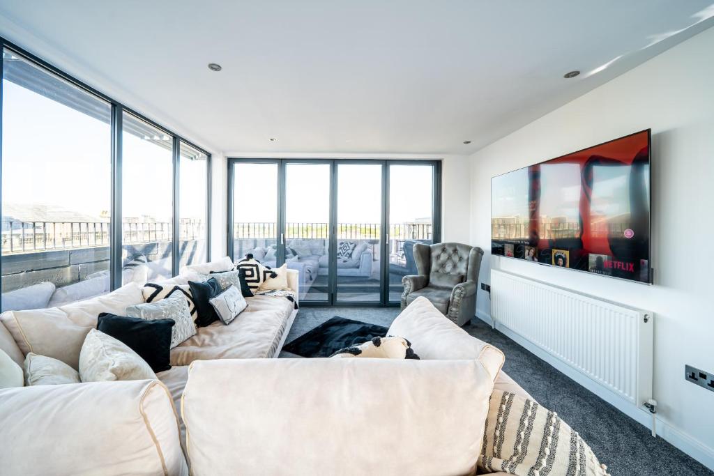 Elle comprend un salon doté d'un mobilier blanc et de grandes fenêtres. dans l'établissement Luxurious 2-Bedroom Penthouse Apartment with Stunning Glass-Wall Views in Barnsley Town Centre, à Barnsley