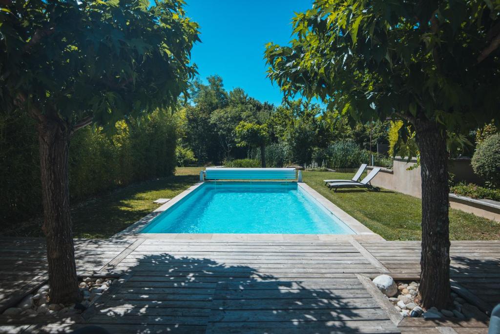 a swimming pool in a yard with two trees at L'ancien poulailler- The Old Hen House in Saint-Saturnin-dʼApt
