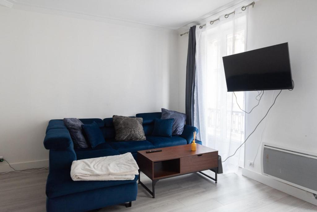 un salon avec un canapé bleu et une télévision dans l'établissement Charming studio near Parc Clichy, à Paris