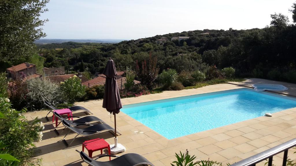 une piscine avec des chaises et un parasol dans l'établissement Villa Piscine-SPA vue grandiose., à Faugères
