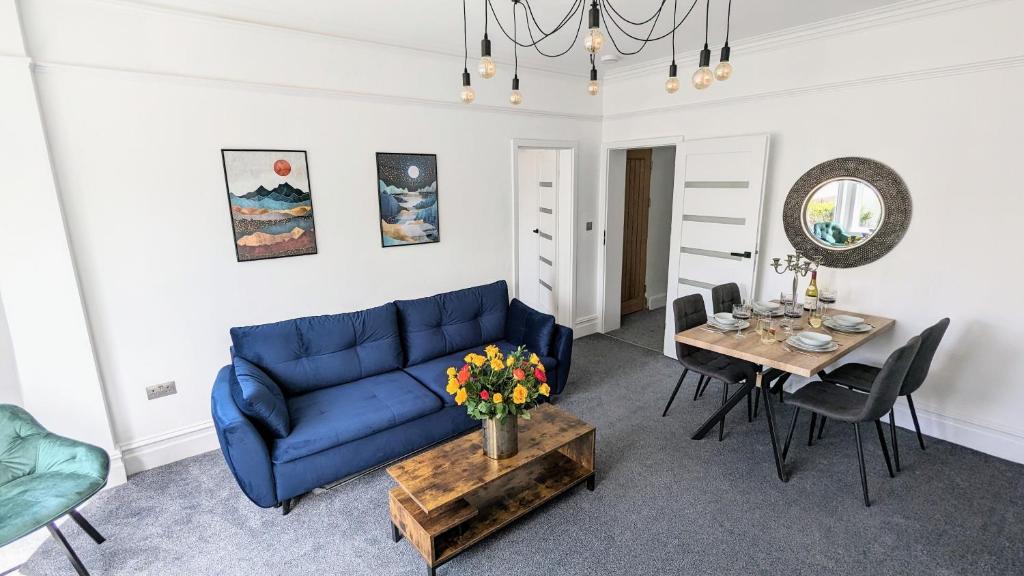 sala de estar con sofá azul y mesa en West Shore Apartment by Seaside Llandudno en Llandudno
