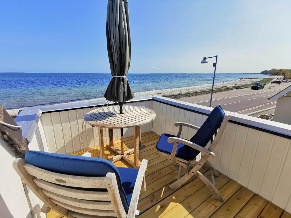Hylleholt的住宿－Seaview，阳台配有2把椅子和1把遮阳伞以及桌子。