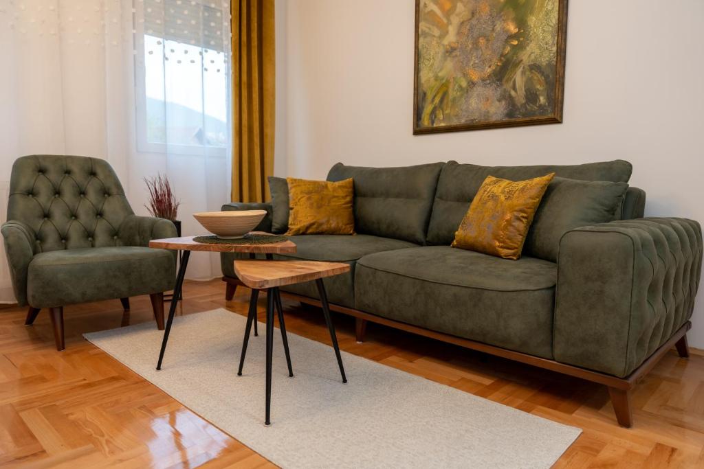 a living room with a green couch and two chairs at Apartman Nest in Vranje