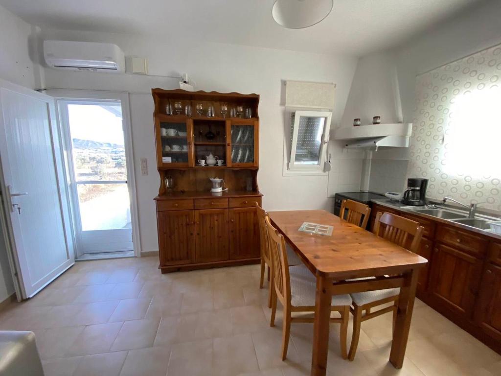 una cocina con armarios de madera, mesa y fregadero en Zefiria Countryside Cottage, en Zefiría