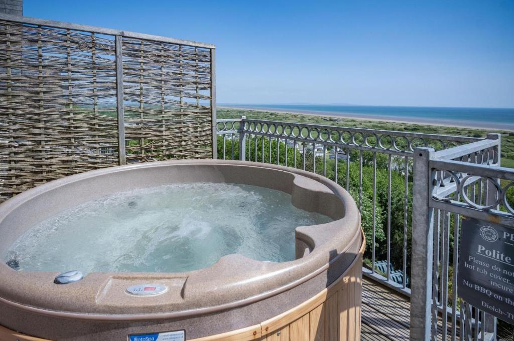 a hot tub on a deck with the ocean in the background at Manor View - 1 Bedroom Apartment - Pendine in Pendine
