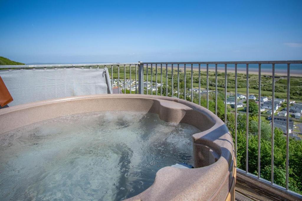 a hot tub on a balcony with a view of the ocean at Campbell - 2 Bedroom Apartment - Pendine in Pendine