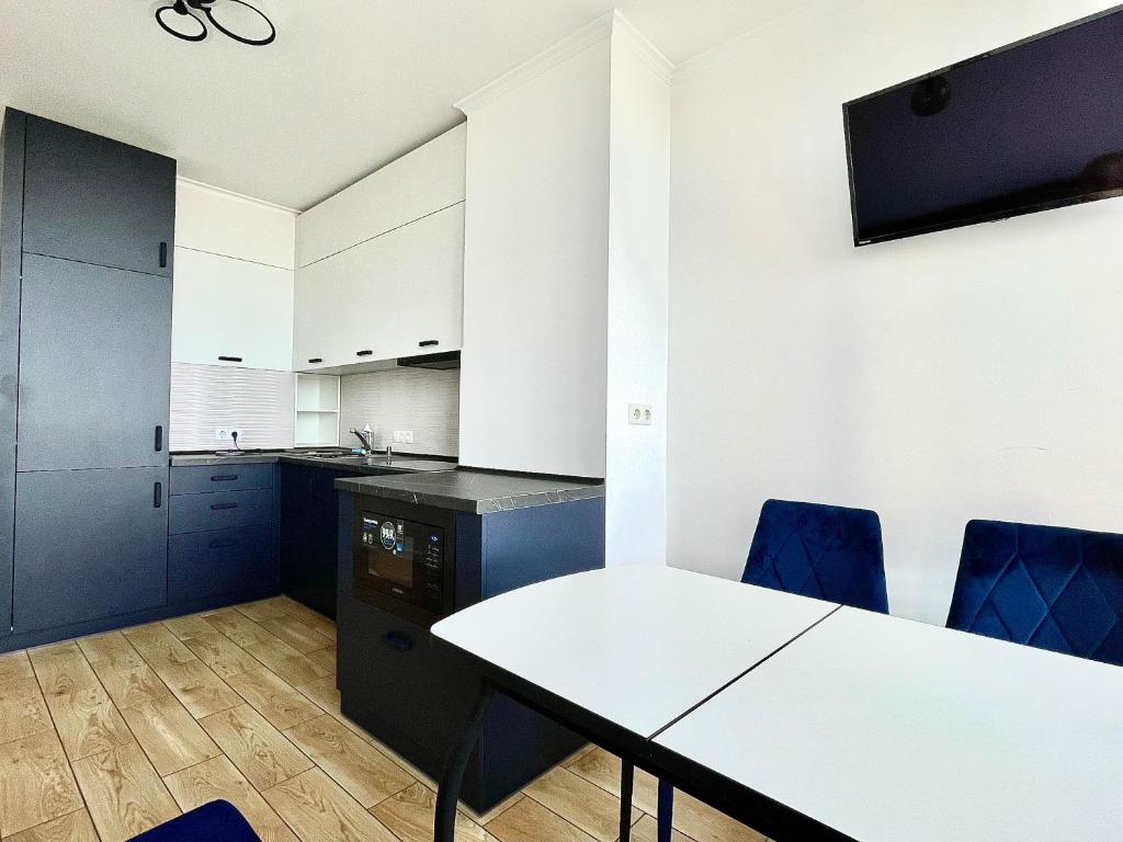 uma cozinha com uma mesa branca e cadeiras azuis em 1-к квартира люкс з видом на Дніпро em Tcherkássi