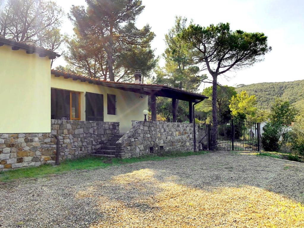 a house with a stone wall and a fence at Elba Villa Colle - Nel verde ma vicina al mare in Marina di Campo