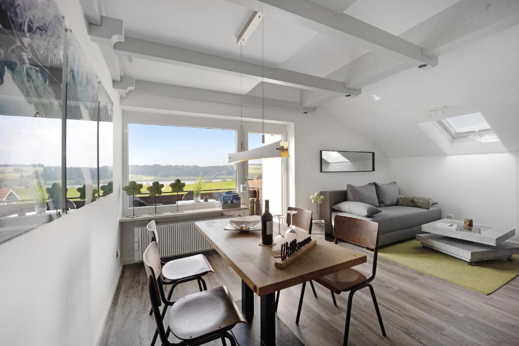 a living room with a table and chairs and a couch at Loft mit Seeblick und Innenpool 