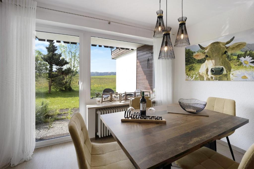 a dining room with a table and a cow picture on the wall at Landliebe mit Seenähe und Innenpool in Petersthal