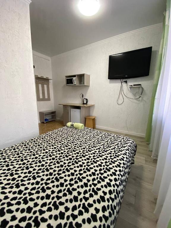 a black and white bed in a room with a tv at Мини-студия напротив парка Металлургов in Ustʼ-Kamenogorsk