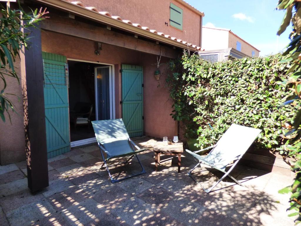 two chairs and a table in front of a house at Les Jardins d&#39;Ulysse, Pavillon T3, terrasse &amp; parking, Narbonne Plage in Narbonne-Plage