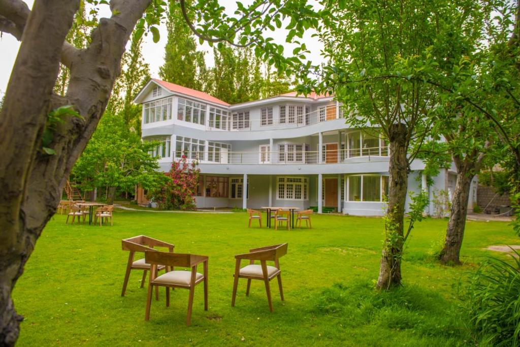 un grande edificio bianco con tavoli e sedie nel cortile di Hotel Reego a Skardu