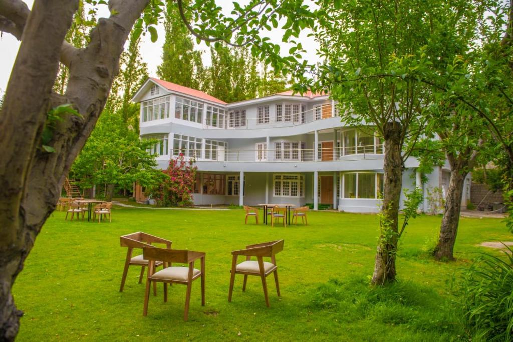 a large white building with tables and chairs in the yard at Hotel Reego in Skardu