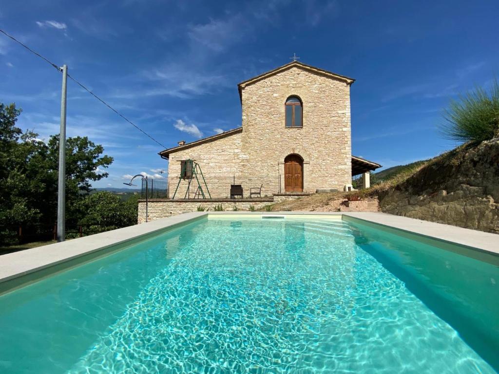 a church with a swimming pool in front of a building at APPARTAMENTI VACANZA SAN SILVESTRO in Piobbico