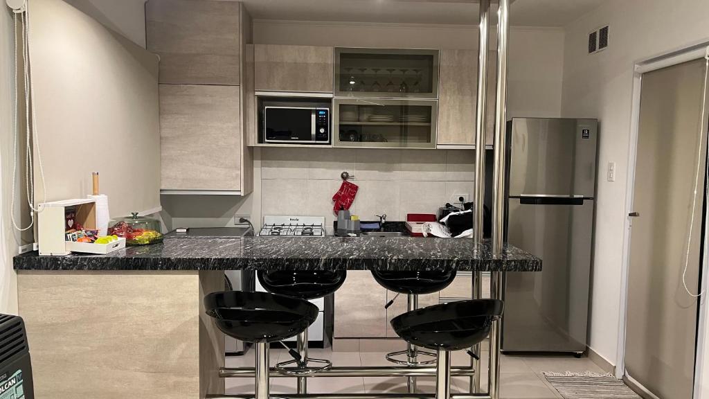 a kitchen with a counter with four bar stools at Depto Parque Urquiza Parana ER in Paraná