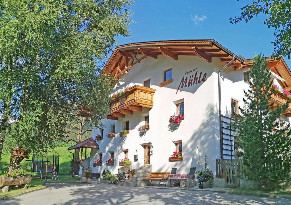 ein großes weißes Gebäude mit einem Holzdach in der Unterkunft Haus zur Mühle in Ried im Oberinntal