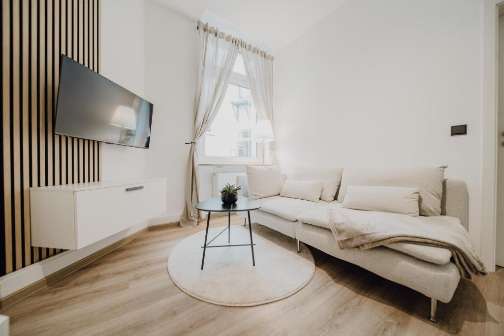 ein Wohnzimmer mit einem Sofa und einem TV in der Unterkunft LLR Design Apartment - Sienna Beige im Zentrum von Koblenz in Koblenz