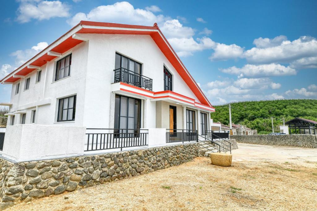 een wit huis met een oranje dak en een stenen muur bij 澎湖奇遇菓海景民宿 in Xiyu
