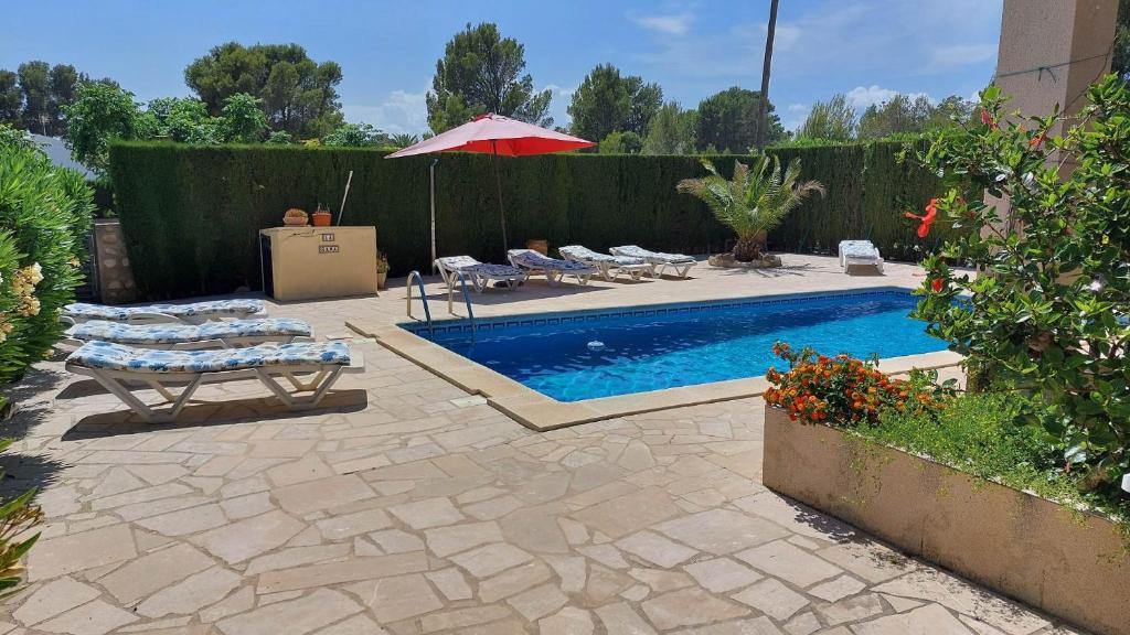a pool with chairs and an umbrella next to a fence at Casa La Rana in Calafat