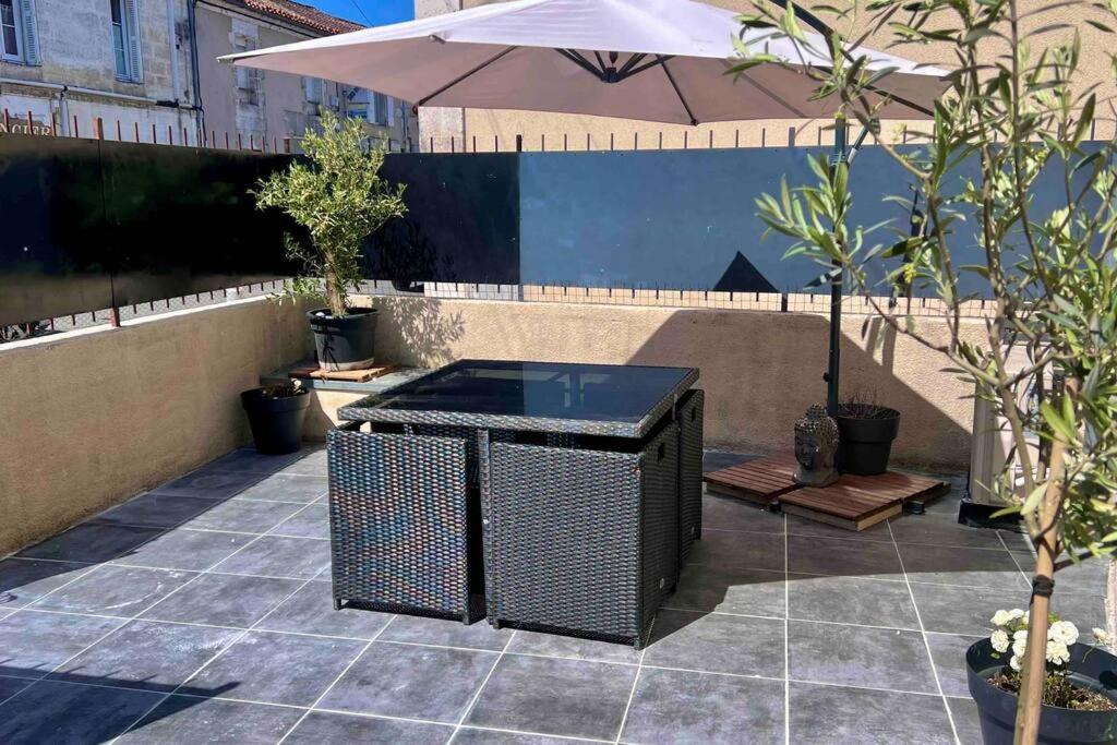 un patio avec une table et un parasol dans l'établissement Maison avec terrasse cosy, 2 chambres, wifi, parking, à Ruelle-sur-Touvre
