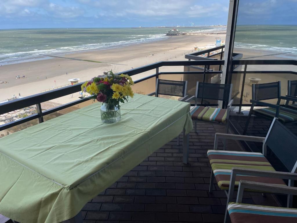 una mesa con un jarrón de flores en la playa en Bristol Palace Seaview 7e verdieping, 30 meter van strand, en Blankenberge