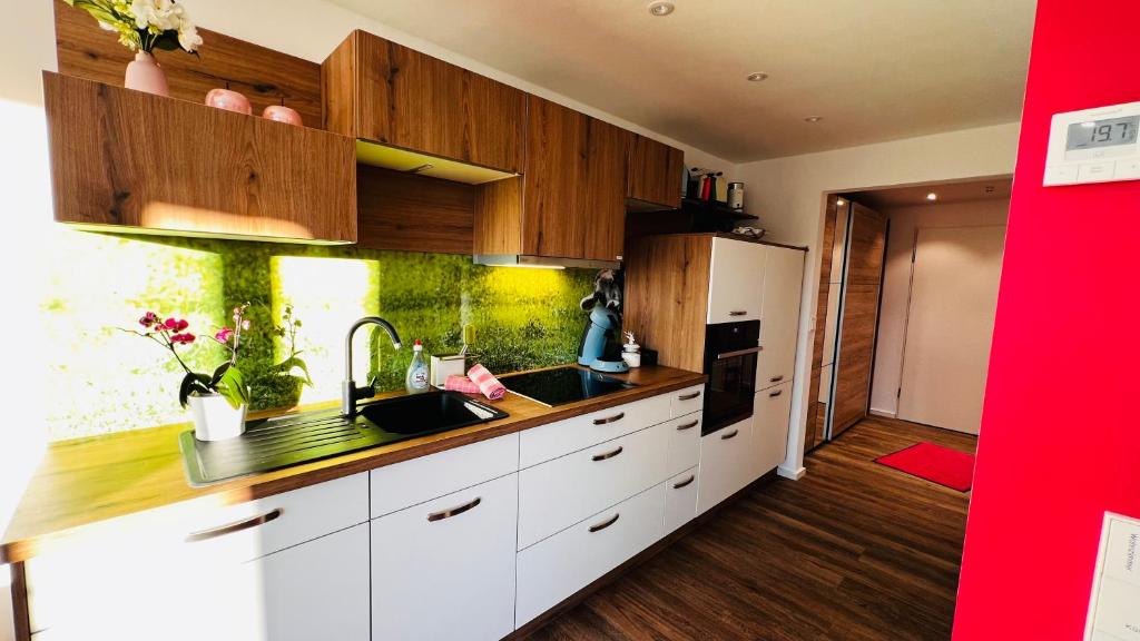 a kitchen with white cabinets and a sink and a refrigerator at Alpenjuwel in Scheidegg